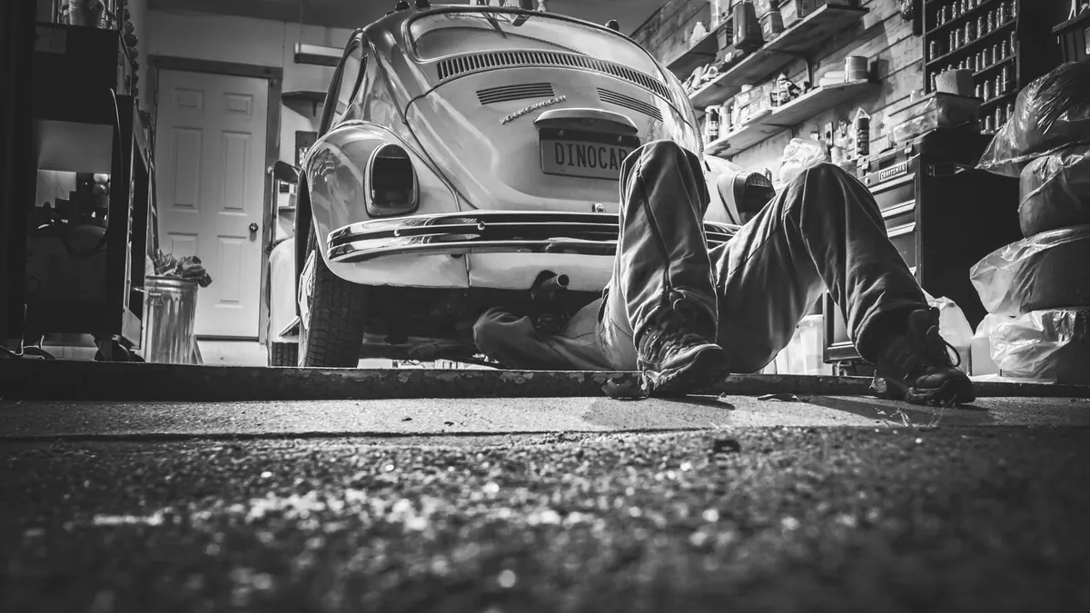 Mécanicien sous une Coccinelle dans un garage ancien